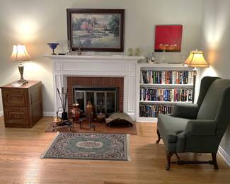 In this room, the side table on the left supports a table lamp, while there is a small area rug in front of the fireplace irons, candle holder, and vases.  There are a lot of books in the sale, not just here, but in other areas.  And the framed artwork and chair, don't forget those.