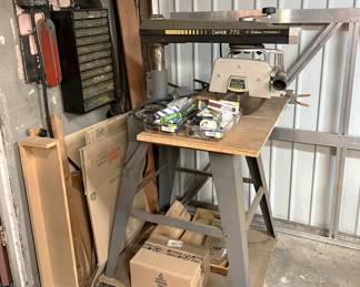 Out in the garage, this radial arm saw is mounted on a mobile platform for working in different areas of the space.  There is also a wall-mounted storage box behind the saw.  There are also lots of woodworking jigs all around the space, so be on the lookout for those.
