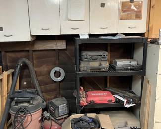 Next to the large shop vacuum is an air compressor, and in the box is a smaller shop vacuum.  There are other woodworking tools in the boxes on the shelf unit.