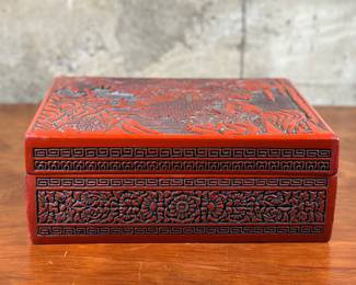 A late 19th century lacquer & hand-carved varnished wood cinnabar box in very good condition. This decorative box with lid measures (closed), 5” H x 13” W x 10.75” D. A cinnabar box is a type of antique Chinese lacquerware box, typically made with a rich red lacquer, known for its intricate carvings and often used for holding keepsakes or small items.