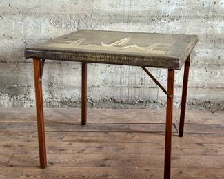 A fantastic card table by Shwayder Bros and marked “Samson Table” circa 1930s. This company later became the infamous Samsonite Luggage Company. Marked “Souvenir Tower of the Sun 1939 World Fair San Francisco” on the front lower left corner. Picture of two bridges, airplanes and pyramid skyscraper. Would be fantastic as an art piece on a wall. This Samson Table measures (when folded out), 25.5” H x 30” W x 30” D.