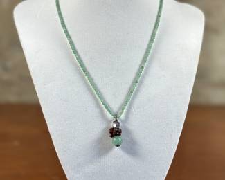 This lot features an artisan made necklace, believed to be a Jadeite pendant with other stones on top. This necklace measures 16” with a gold-colored clasp.