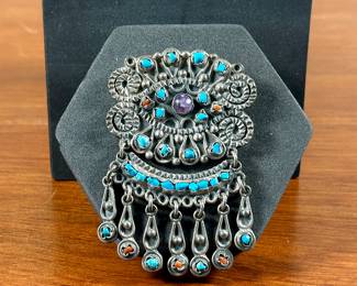 A stunning Taxco brooch or pendant with sterling silver, Turquoise, Amethyst, & Coral. Marked on the back, “Mexico 925″ with maker’s mark as shown in photos. This brooch measures 3” H x 2” W. Includes a loop on back to use as a pendant or a pin to display as a brooch. Total approx. weight is 39.00 grams.