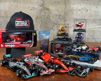 This lot features an assortment of Formula 1 model cars and collectibles including many manufactured by Bburago. Also included are helmet models from racer, Lewis Hamilton in various years with display stands and covers, along with a hat, collectible cup & models still in the box. There are a total number of 17 items in this lot.