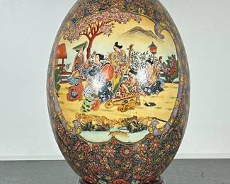 MONUMENTAL CERAMIC EGG | Monumental Asian ceramic egg decorated with figural scenes with flowers & butterfly’s with gilt accent, on wood stand. - h. 20 x dia. 13 in
