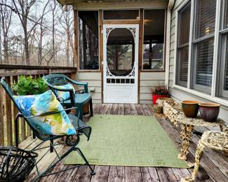 Back porch with cast iron garden chair, table, and planter.