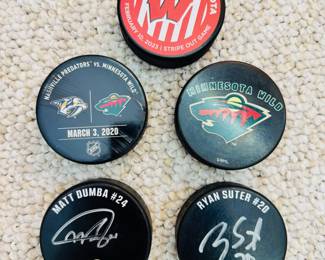 U of M vs Wisconsin Stripe Out Game hockey puck and MN Wild Hockey Pucks, including one signed by Matt Dumba #24 and one by Ryan Suter #20