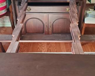 The pullout drawer is fully extended here.  Inside you can see four leaves that can be taken out and placed on the pieces of the table that is extended. .  The table could seat six to eight .  The end of one side is the front drawer and the other side is the rest of the cabinet.  Awesome!