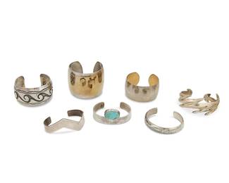 306
A group of Southwest-style silver cuff bracelets
Late 20th century
Three marked for sterling; one further marked for maker: AT [conjoined]
Seven works comprising an Alvin Thompson (b. 1955, Diné) Navajo chunky cast sterling silver cuff with zigzag shaping and arrow terminals, as well as a narrow sterling cuff with set turquoise cabochon, and a wide cuff with shadowbox wave forms and stamped banding, together with four further plain cuffs in various shapes and sizes, 7 pieces
Largest: 7" total inner C x 2" H, with a 0.75" gap; smallest: 6.25" total inner C x 0.5" H, with a 1" gap
282.1 grams gross
Estimate: $100 - $200