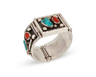 220
A Southwest sterling silver and stone set bracelet
Late 20th century
Marked: JB / Sterling
A chunky hinged bangle bracelet with integral decorative clasp and hinge, with various shapes of set turquoise and coral stones amid silver dot and wire overlay designs
6" inner C x 1.25" H
119.6 grams gross
Estimate: $300 - $500