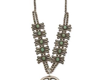 134
A Harry Morgan Navajo silver and turquoise squash blossom necklace
Harry Morgan (1946-2008, Diné)
Late 20th/21st century
Stamped: H Morgan / Sterling
A delicate sterling silver necklace with a central silver blossom naja and ten repoussé silver box concho-style blossoms with set turquoise cabochons, all suspended from two strands of silver beads
24 " L x 2.5" H
112.6 grams gross
Estimate: $700 - $900