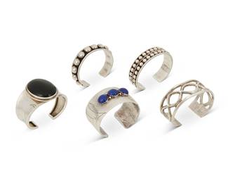 317
A group of Southwest and Mexican sterling silver cuff bracelets
Late 20th century
Five works:

Frank Chee (b. 20th century, Diné)
A Navajo sandcast silver cuff
Stamped: F. Chee / Navajo / Sterling
An openwork cuff with intertwining motif
6.5" total inner C x 1.125" H, with a 1.125" gap

Lorencita Garcia (1938-2005, Kewa)
A Santo Domingo Pueblo set stone cuff
Stamped: LG
A chunky cuff with three row-set lapis lazuli cabochons and concentric engraving to each terminal
6.25" total inner C x 1.375" H, with a 1" gap

A large Southwest-style onyx set cuff bracelet
Stamped: LA [star] / Sterling
With a large central oval onyx cabochon and curved engraving to each tapered terminal
6" total inner C x 1.75" H, with a 0.875" gap

Two Mexican silver cuffs
Each marked: Mexico / Sterling / TA-165
Each with silver ball banding, 2 pieces
Larger: 6.875" total inner C; smaller: 6.5 " total inner C; each with a 1" gap; 0.625" H

5 pieces total
273.6 grams gross
Estimate: $600 - $800