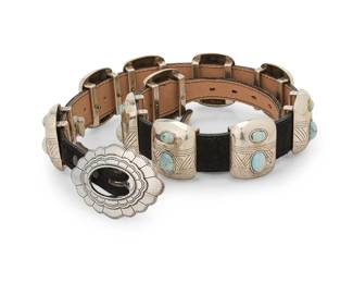 198
A Southwest-style concho belt
Late 20th century
Unmarked
Comprising a chunky belt with ten silver-toned mixed metal conchos with set faux stones, with an associated silver-toned buckle, all mounted to an associated black suede belt
Buckle: 2" H x 3.25" W; each concho: 2" H x 1.5" W; belt: 37" L x 1.25" H
647.2 grams gross
Estimate: $300 - $500