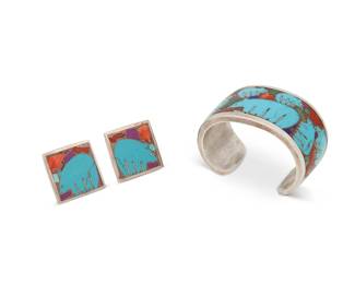 318
A set of Southwest sterling silver and turquoise inlay pictorial bear jewelry
Late 20th century
Each marked verso: Sterling / [unknown pictograph]
Comprising a heavy cuff with various sized blue stone inlay bears and small pieces of lapis, coral, and malachite, all surrounded by copper or enamel, together with a pair of matching clip earrings, 3 pieces
Cuff: 6.125" total inner C x 1.375" H, with a 1.125" gap; earrings: 1.125" H
139.1 grams gross
Estimate: $200 - $400
