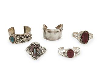 252
A group of Southwest-style silver cuff bracelets
Late 20th century
Variously stamped: four for sterling; three for maker: AL / Masha / Stu Mons [?] Navajo [illegible etched marks]
Comprising an Augustine Largo (b. 20th century, Diné) Navajo three-wire cuff with set spiny oyster and silver floral and feather overlay, a Navajo two-wire cuff with multiple set purple shell stones and elaborate silver overlay, and a chunky "Masha" sterling silver cuff with set turquoise cabochon flanked by an elaborate overlay cluster of silver balls, wire and feather motifs, as well as a delicate sterling two-wire cuff with spiny oyster and floral motifs, and a chunky incised sterling silver "feather" cuff, 5 pieces
Largest: 6.75" total inner C x 1.25" H, with a 1.125" gap; smallest: 6" total inner C x 1" H, with a 1" gap
201.7 grams gross
Estimate: $200 - $400