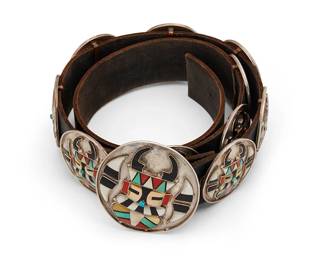 194
A Joe & Cornelia Bowannie Zuni katsina inlay concho belt
Joe and Cornelia Bowannie (each b. 20th century, Zuni Pueblo)
20th century
Etched verso: Joe & Cornelia Bowannie
A belt with raised stone and shell mosaic inlay including turquoise, spiny oyster and other shells set to a large round buckle and ten smaller conchos, each depicting a stylized Zuni mask of possibly Yamuhakto, the wood carrier katsina, and all set to a black leather strap
Buckle: 3" Dia.; each concho: 2.25" Dia.; strap: 40.5" L x 1.625" H
352.7 grams gross
Estimate: $800 - $1,200