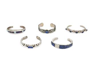 250
A group of Southwest cast sterling silver and stone cuff bracelets
Late 20th century
Each marked for sterling and for maker: D. Reeves / A / LJ / FL Begay / TK [conjoined with feathers for Ray Tracey/Knifewing Segura]
Five sterling silver cuffs each with lapis lazuli, comprising a David Reeves (b. 1949-d., Diné) Navajo shaped stampwork cuff, an F.L. Begay (b. 20th century, Diné) Navajo chunky cuff with central rectangular lapis and set lapis to each terminal, a Lester Jackson (b. 1951, Diné) Navajo chunky cuff with lapis lazuli and textured silver raised inlay, as well as a Ray Tracey / Knifewing Segura (b. 1953, Diné & b. 20th century, Chiricahua Apache) tapered cuff with lapis, turquoise, and sugilite channel inlay, and a narrow openwork cuff with five set lapis cabochons, 5 pieces
Largest: 6.25" inner C x 0.375" H, with a 1.125" gap: smallest: 6" inner C x 0.5" H, with a 1" gap
170.8 grams gross
Estimate: $400 - $600