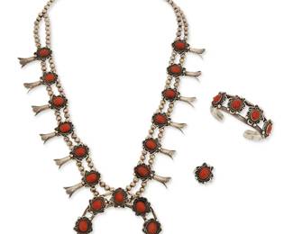 131
A set of Southwest silver and coral squash blossom jewelry
Mid/late 20th century
Unmarked
Comprising a necklace with a central two-wire naja with set coral and silver filigree wire edging, with twelve set coral and silver "blossoms", all suspended from a double strand of silver beads, together with a matching set coral two-wire cuff bracelet, and a matching ring, 3 pieces
Necklace: 24.5" L x 2.875" H; cuff: 6.125" total inner C x 0.875" H, with a 1" gap; ring size: 7.5
209.3 grams gross
Estimate: $700 - $900