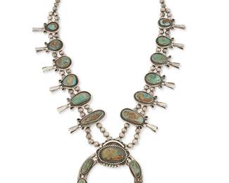 133
A Navajo sterling silver and turquoise squash blossom necklace
Mid/late 20th century
Unmarked
Featuring a large sterling silver two-wire naja with graduated set turquoise, and with twelve chunky graduated set turquoise blossoms, all suspended from two strands of silver beads
29.5 " L x 3.75" H
313.2 grams gross
Estimate: $700 - $900