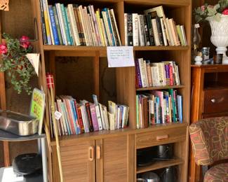Book case with lots of books, Roasting pan on top, Camping pans at bottom