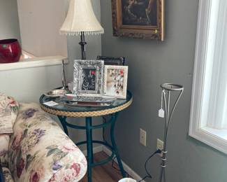 Glass top side table, Table lamp with shade, beautiful silver pieces, picture frames, tall candle holder, art piece