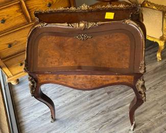 Here's a description you can use for your estate sale listing, focusing on the key features and appealing to potential buyers:
Elegant Antique French-Style Roll-Top Writing Desk with Ormolu Mounts
This charming writing desk is a beautiful example of French-inspired design, reminiscent of the Louis XV period. Its elegant curves, cabriole legs, and ornate ormolu (gilt bronze) mounts make it a striking addition to any home.