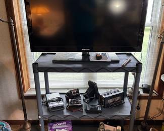 A nice shelf filled with lots of electronics and cameras! Vinatge to modern! Then TV is a Samsung and has the original remote, power cord, and manual.