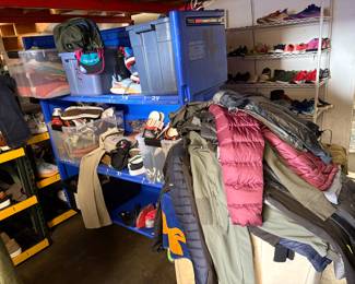 A massive bin of coats hoodies and vintage to be priced. A rack of shoes pants and hoodies to be priced 