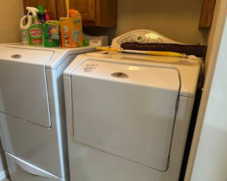 Maytag washer and dryer set on stands with drawers.