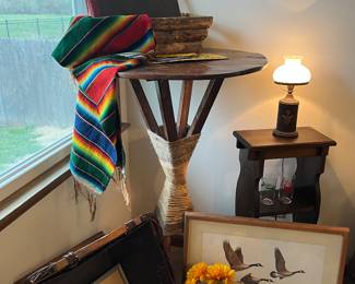 Signed artwork, tall table and antique lamp.