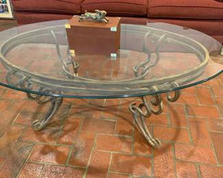 Contemporary and ornate oval glass - metal coffee table.