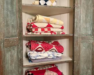 Antique painted corner cupboard and selection of quilts
