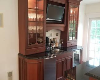Handsome bar with refrigerator and space for wine cooler. Illuminated glass upper cabinets. Approximately 8 feet long