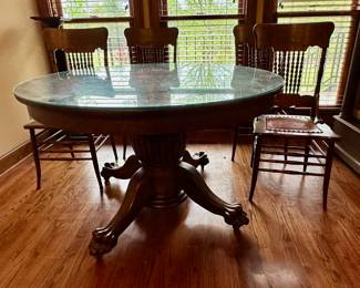 Round lions paw pedestal table with four leather seat chairs. Detail of leather seat in next picture.