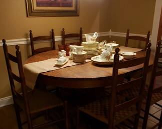Antique dining table made of quarter sawn oak. Includes two leaves. Six dark maple ladder back dining chairs.