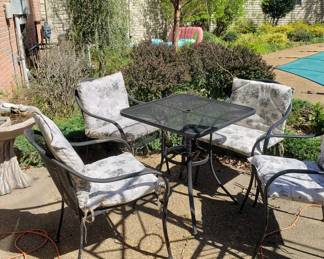 Square wrought iron patio table and 4 wrought iron chairs with cushions.