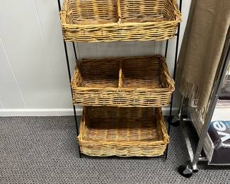 Vintage three-tiered basket stand with black iron and three woven wicker baskets.