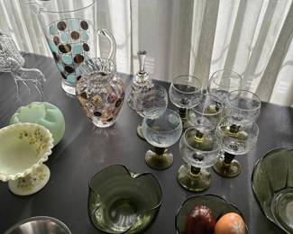 In the living room, there’s a banquet table filled with small vintage glassware, all in terrific condition