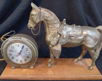 LOT #9: Brass clock with horse on wooden base.
No visible markings or signature. Base is 16" x 4 1/2". Horse is 11" tall. Weighs 8 pounds. The clock works.