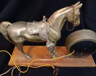 Brass clock with horse on wooden base.
No visible markings or signature. Base is 16" x 4 1/2". Horse is 11" tall. Weighs 8 pounds. The clock works.