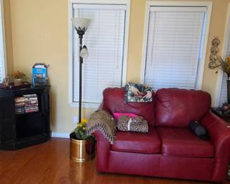 Leather love seat in sunroom with table in corner & stand lamp