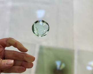 Detail  as show holding transparent vintage (1700’s) bullseye glass pane.  Greenish pane shown in the background. 