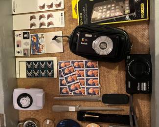 Marilyn Monroe and other $.32 stamps, on/off timer, letter openers, padlock w/ combo, Nikon color pix camera, Kodak retinas camera and new box of cell phone screen protectors.