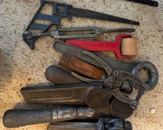 Antique hand tools including saws, hole punch, and crimping tools used for cutting, shaping and joining materials. Unique features.