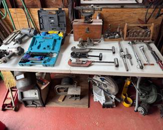 Collection of power tools and hand tools including clamps, drills, saws, and floor jack.