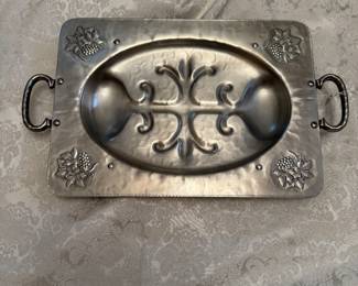 Well-known aluminum craftsman handcrafted platter with intricate design and hammered finish. Designed for serving and carving meat, featuring a central well to collect juices and raised edges to prevent spills.