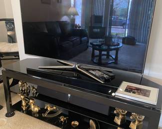 Samsung 55" TV, sound bar and, black metal and glass media console, and brass decor