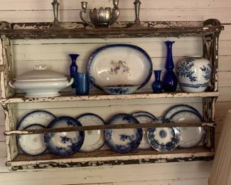 Primitive white plate holder with various flow-blue pieces.