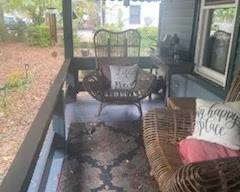This porch has a few great finds! 2 matching chairs, 2 matching carved teak end table, one grey wooden demi-lune table, 2 matching outdoor rugs, lanterns, and an assortment of small pots