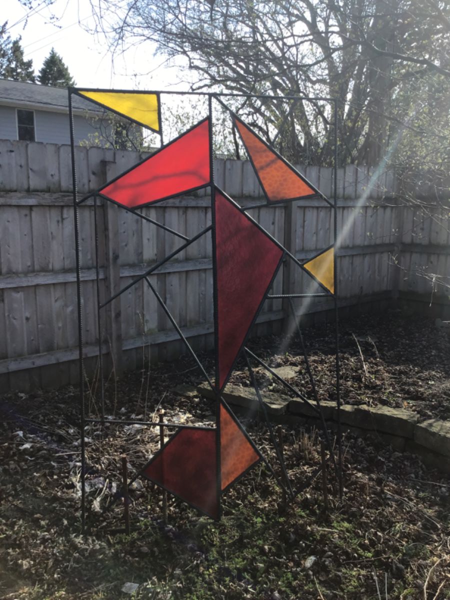 Great piece of garden art. made of rebar and plexiglass with yellow orange and red shapes.